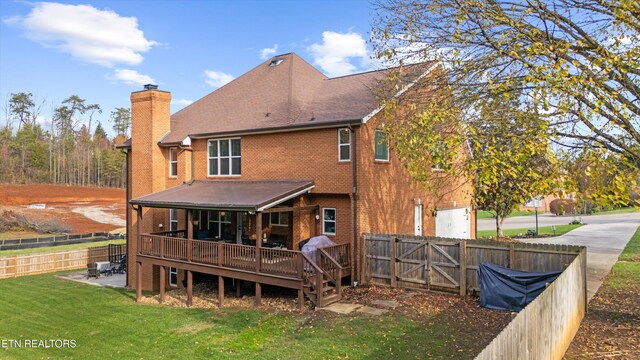 back of property with a lawn and a deck