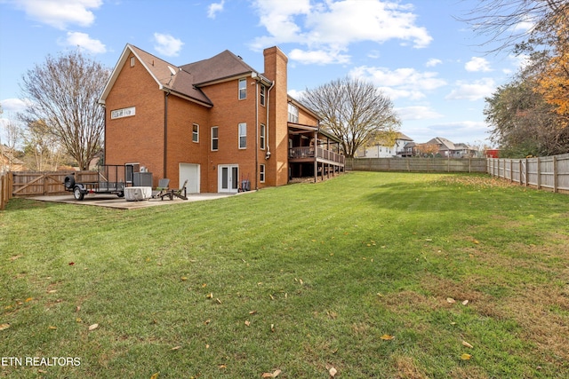 rear view of property featuring a deck, a patio area, and a lawn