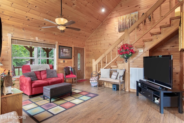 living room featuring high vaulted ceiling, hardwood / wood-style floors, wood walls, and ceiling fan