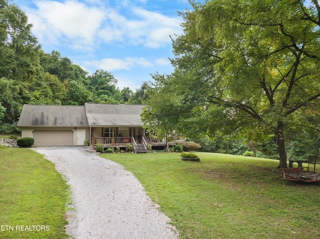 view of front of home featuring a garage, a front yard, and covered porch