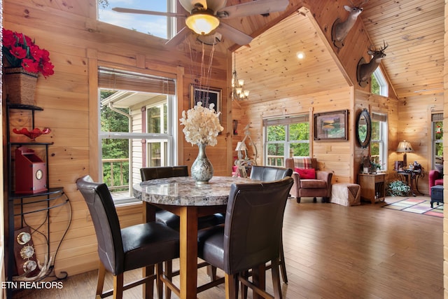 dining area featuring hardwood / wood-style flooring, plenty of natural light, wood walls, and ceiling fan