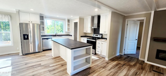 kitchen with white cabinets, a center island, wall chimney exhaust hood, stainless steel appliances, and light hardwood / wood-style flooring