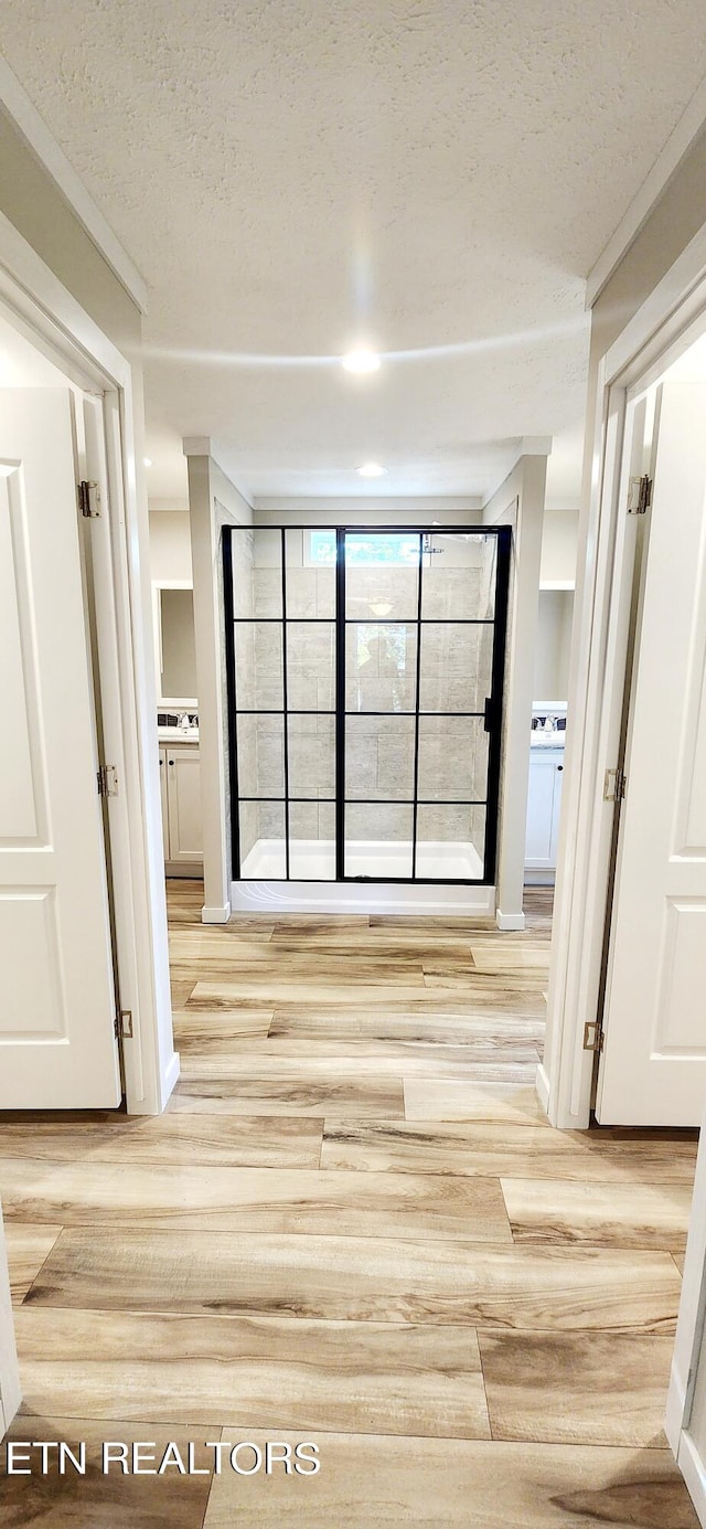 hallway featuring light hardwood / wood-style flooring and a textured ceiling