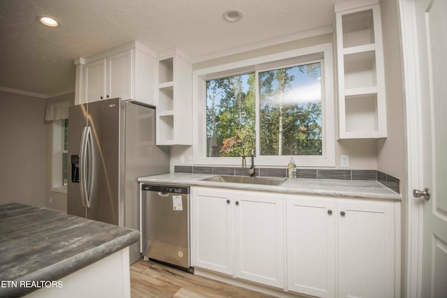 kitchen featuring sink, light wood-type flooring, white cabinetry, and appliances with stainless steel finishes