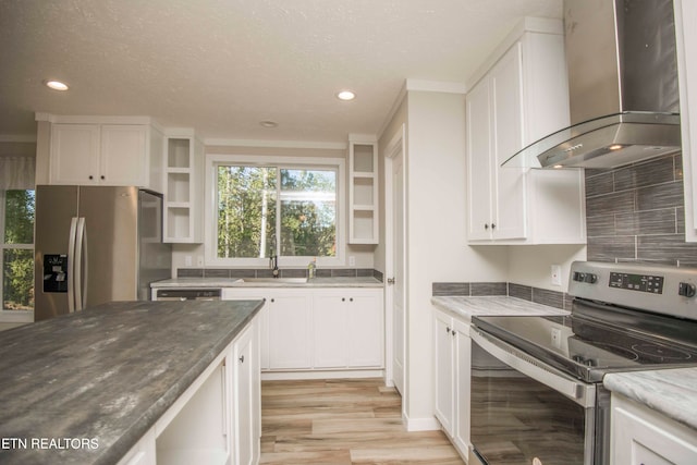 kitchen with wall chimney exhaust hood, white cabinets, and stainless steel appliances