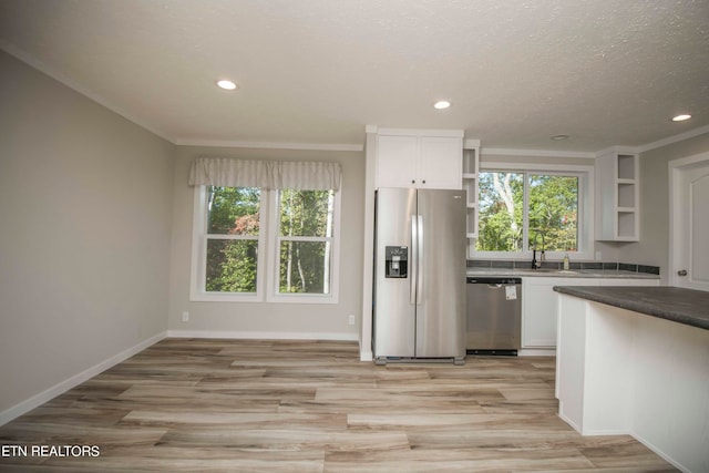 kitchen featuring white cabinets, stainless steel appliances, ornamental molding, and a textured ceiling