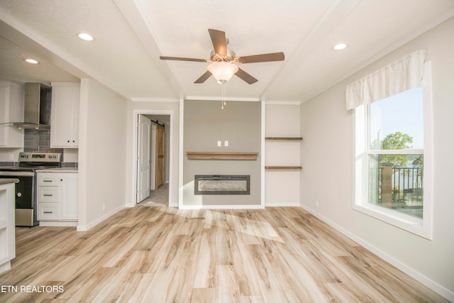 unfurnished living room with ceiling fan, crown molding, and light hardwood / wood-style floors