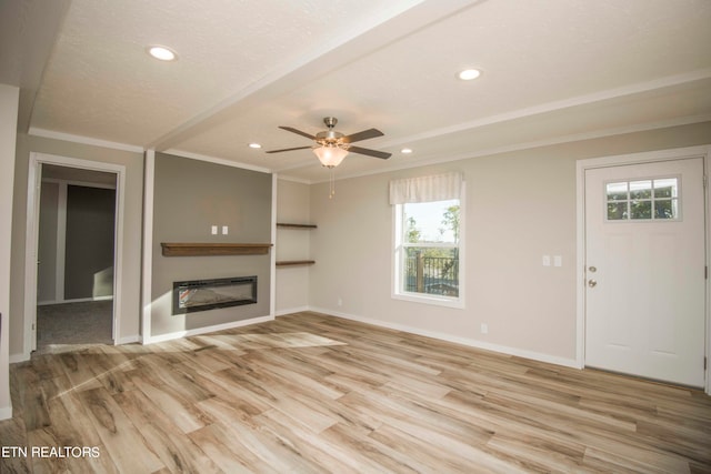 unfurnished living room featuring light wood-type flooring, ceiling fan, a wealth of natural light, and ornamental molding