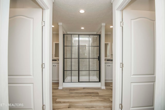 hallway with crown molding, a textured ceiling, and light hardwood / wood-style flooring