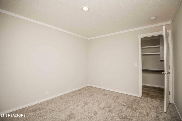 unfurnished bedroom featuring a textured ceiling, carpet floors, and ornamental molding