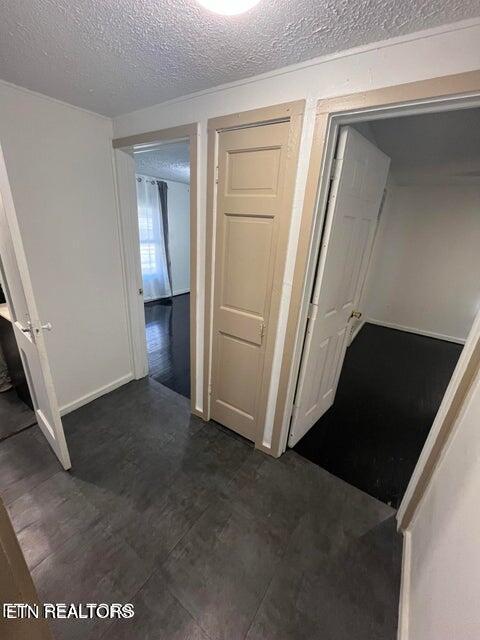 corridor with a textured ceiling and baseboards