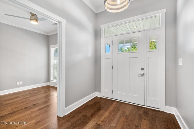 foyer entrance with ornamental molding, dark wood-type flooring, and ceiling fan