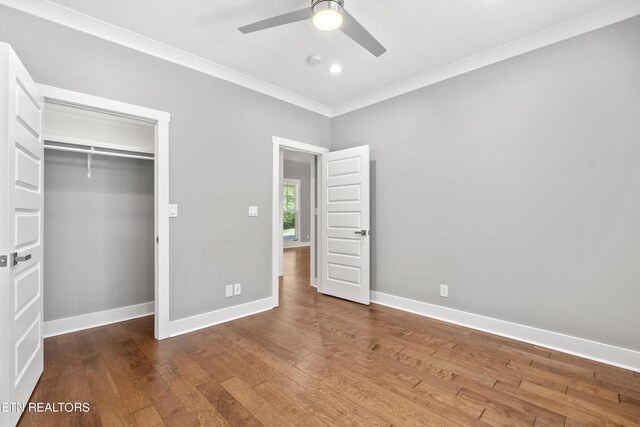 unfurnished bedroom with crown molding, wood-type flooring, a closet, and ceiling fan