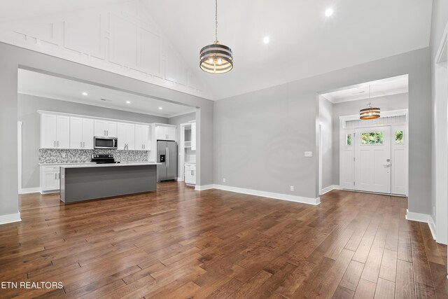 interior space featuring hardwood / wood-style flooring, stainless steel appliances, a center island, pendant lighting, and white cabinets