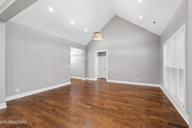 unfurnished living room featuring a chandelier, high vaulted ceiling, and dark wood-type flooring