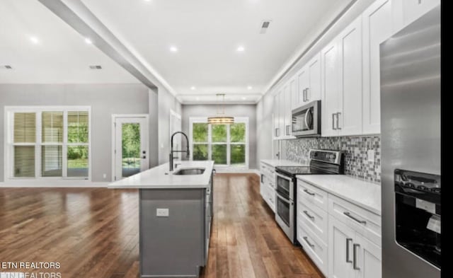 kitchen featuring sink, appliances with stainless steel finishes, white cabinets, and an island with sink