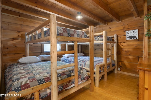 bedroom with beam ceiling, wood walls, light hardwood / wood-style flooring, and wooden ceiling