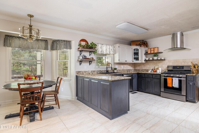 kitchen with an inviting chandelier, sink, gas range, gray cabinetry, and wall chimney range hood