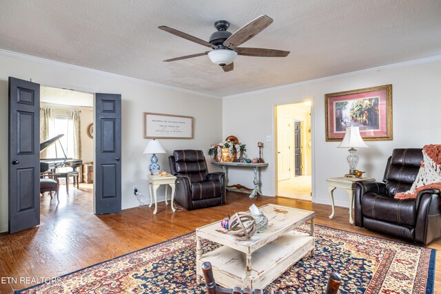 living room featuring ornamental molding, a textured ceiling, wood-type flooring, and ceiling fan