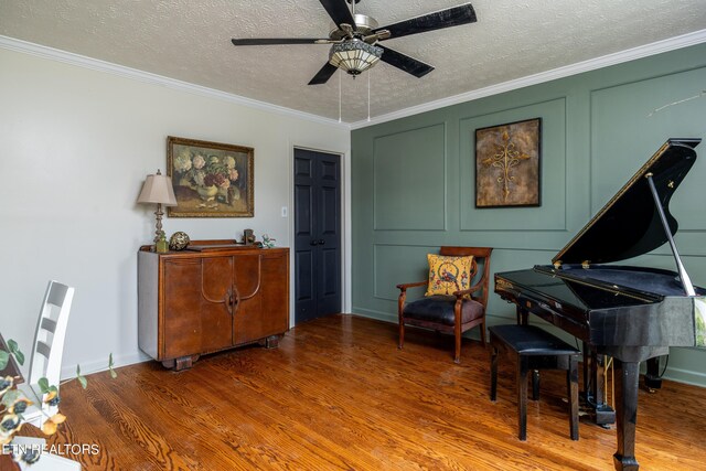 sitting room with ornamental molding, a textured ceiling, wood-type flooring, and ceiling fan