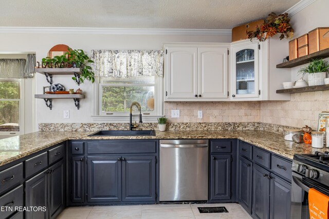 kitchen with white cabinets, crown molding, stainless steel dishwasher, sink, and dark stone counters