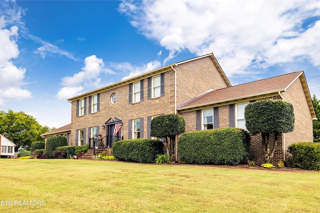 colonial home featuring a front lawn and brick siding