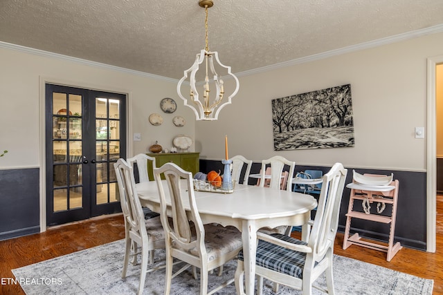 dining room with a notable chandelier, french doors, crown molding, and wood finished floors