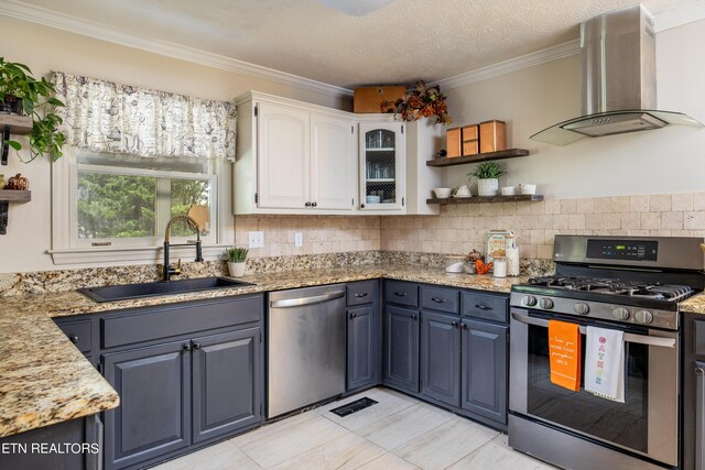 kitchen featuring stainless steel appliances, white cabinetry, sink, wall chimney range hood, and a textured ceiling