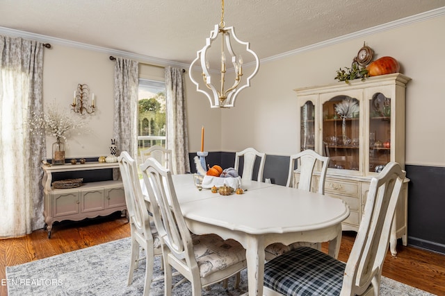 dining area with an inviting chandelier, crown molding, wood finished floors, and a textured ceiling