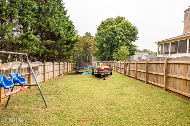 view of yard featuring a playground, a sunroom, and a trampoline