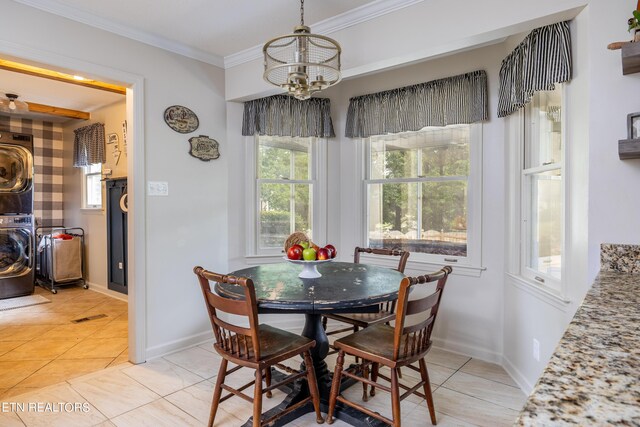 tiled dining area featuring stacked washer and clothes dryer, a notable chandelier, and ornamental molding