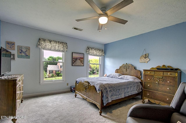 carpeted bedroom featuring visible vents, baseboards, a textured ceiling, and ceiling fan