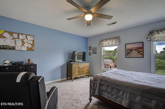 carpeted bedroom featuring visible vents, multiple windows, a textured ceiling, and baseboards