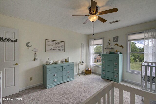 carpeted bedroom featuring ceiling fan and a textured ceiling