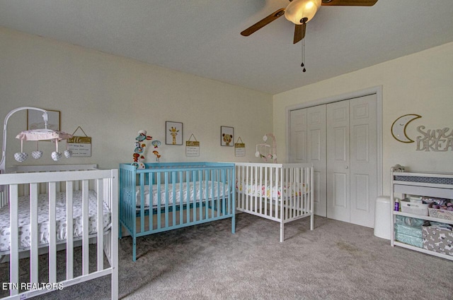 bedroom featuring a ceiling fan, a crib, carpet, and a closet