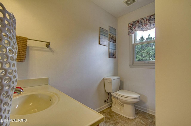 bathroom with vanity, toilet, baseboards, and visible vents