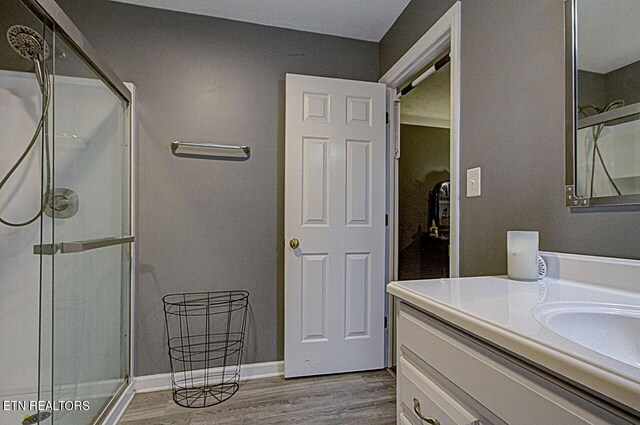 bathroom with a shower with door, hardwood / wood-style flooring, and vanity