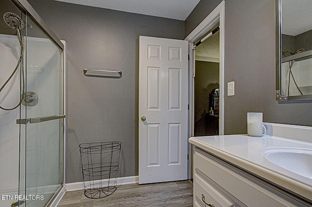 bathroom featuring a shower stall, vanity, baseboards, and wood finished floors