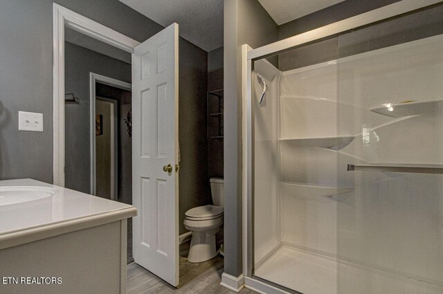 bathroom with a shower with door, hardwood / wood-style floors, toilet, vanity, and a textured ceiling