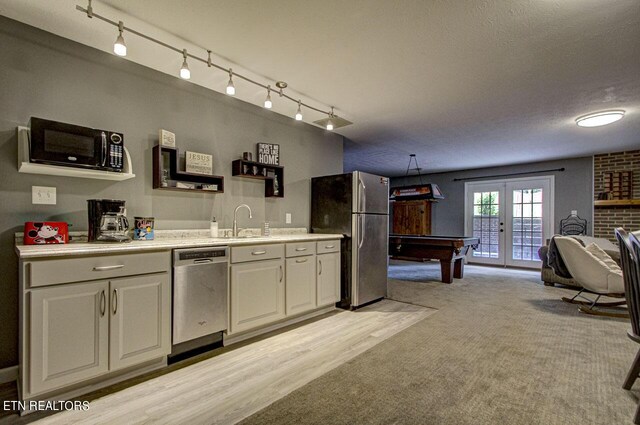 kitchen with billiards, appliances with stainless steel finishes, french doors, sink, and white cabinets