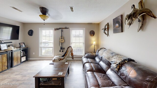 living room featuring a textured ceiling, ceiling fan, and wood-type flooring