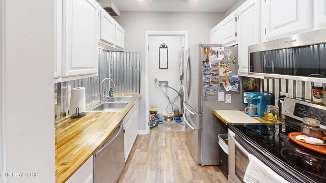 kitchen featuring white cabinets, stainless steel appliances, sink, and light hardwood / wood-style floors