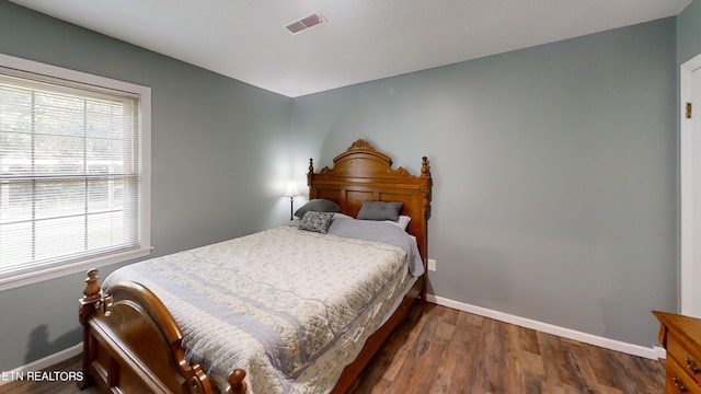 bedroom with multiple windows and dark hardwood / wood-style floors