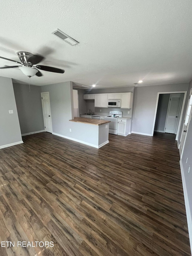 unfurnished living room with a textured ceiling, ceiling fan, dark hardwood / wood-style floors, and sink