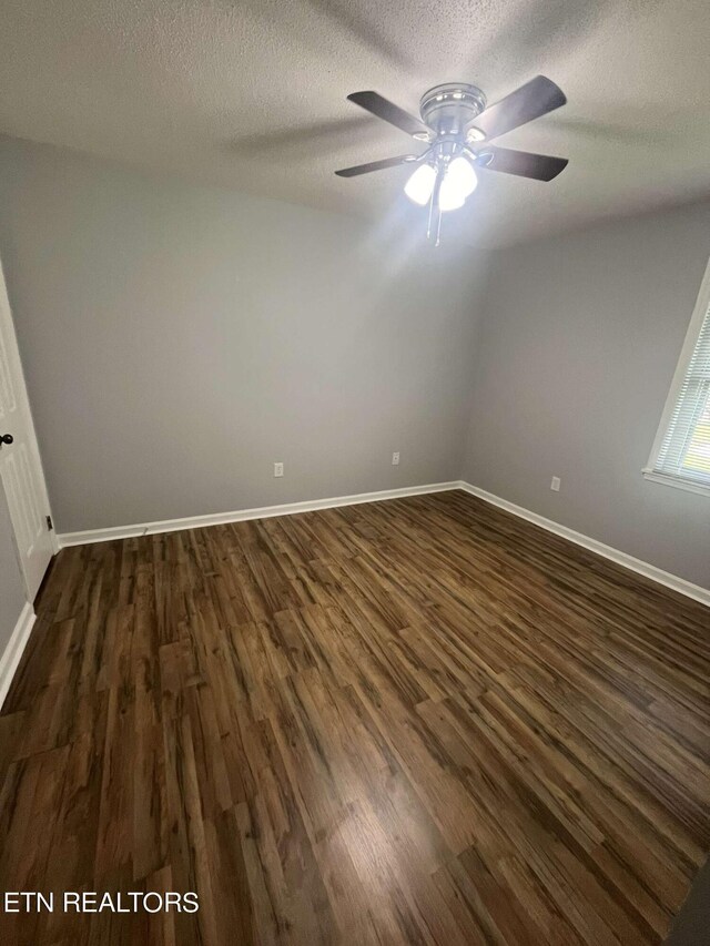 empty room with ceiling fan, dark hardwood / wood-style flooring, and a textured ceiling