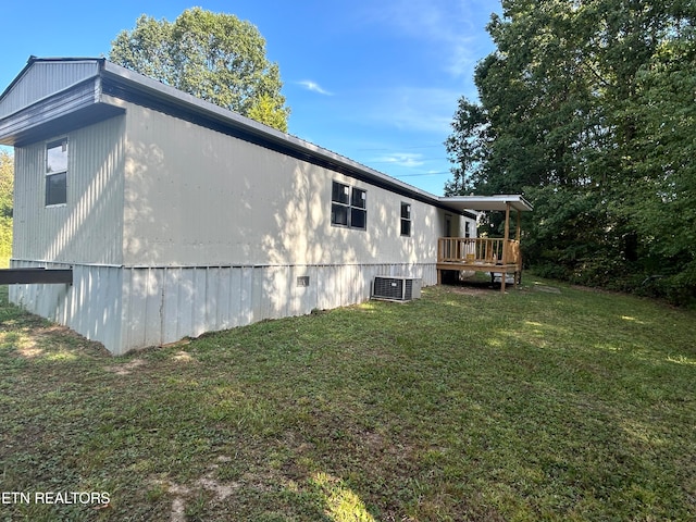 view of side of property with a deck, a lawn, and central AC