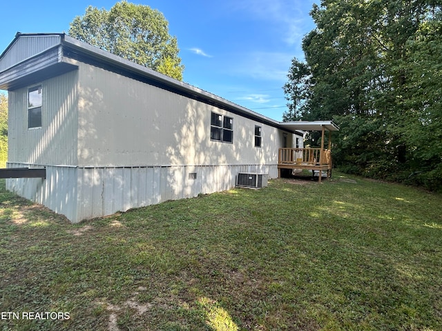 view of side of home featuring a wooden deck, a yard, and cooling unit