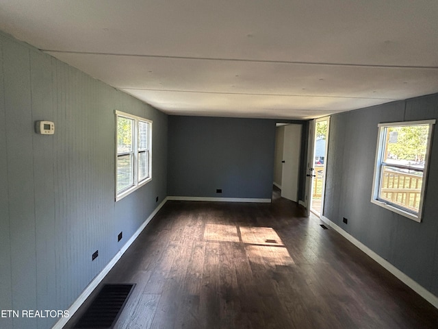 empty room with dark wood-type flooring and a wealth of natural light