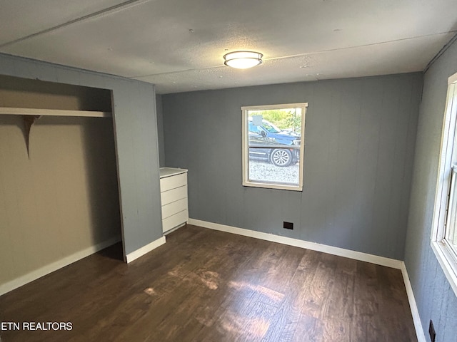 unfurnished bedroom with a closet and dark hardwood / wood-style flooring