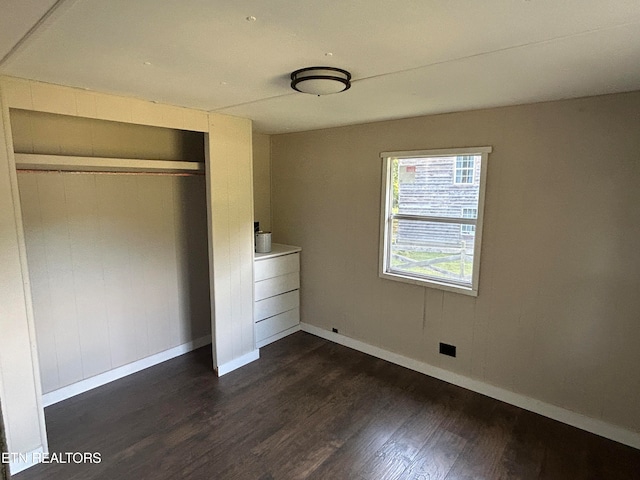 unfurnished bedroom featuring dark wood-type flooring and a closet